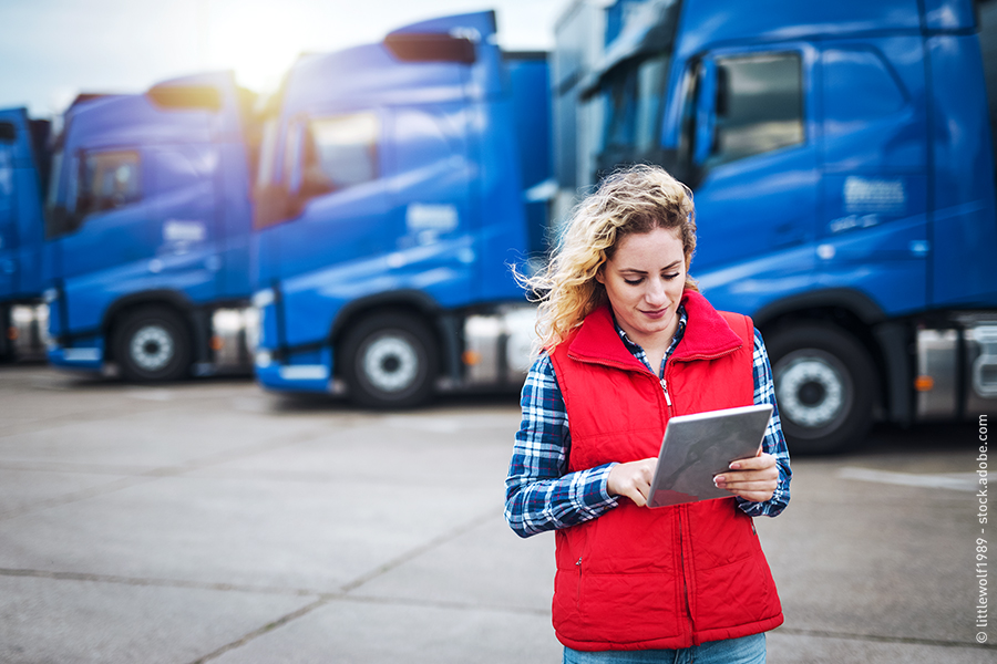 woman with tablet in front of trucks