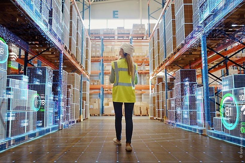 a-woman-with-a-warning-vest-walks-through-a-digitised-warehouse